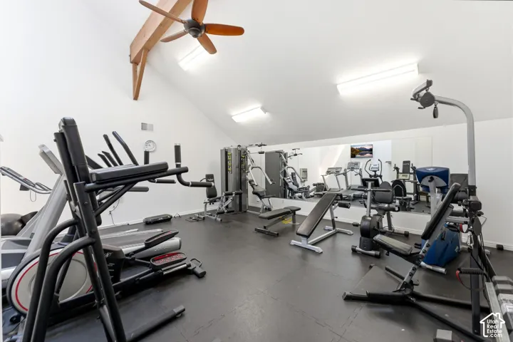 Vaulted ceiling with exposed wood beams, ceiling fan, mirrored wall, recessed lighting, and resilient flooring