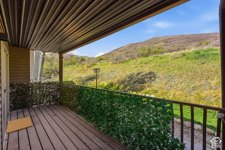 Covered deck with wood-finish flooring, metal railing, and expansive natural scenery