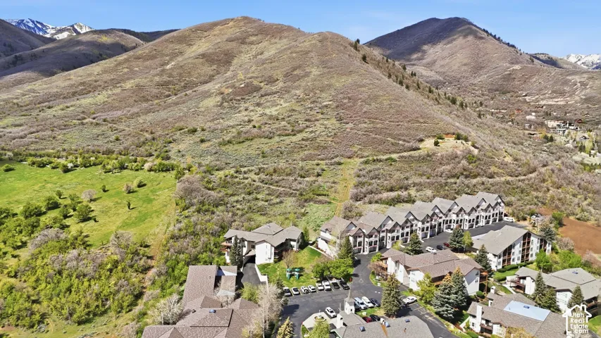 Mountainous terrain, multi-unit residential buildings, paved parking areas, and surrounding natural landscaping