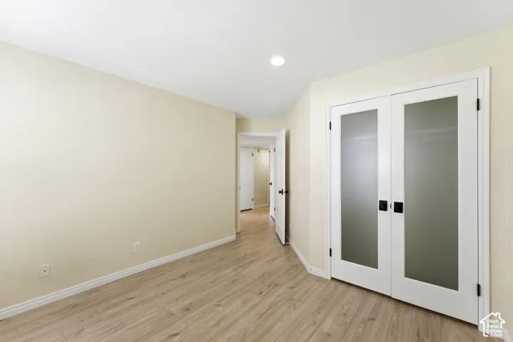 Wood-finish flooring, recessed lighting, and a white double door with frosted panels and black hardware