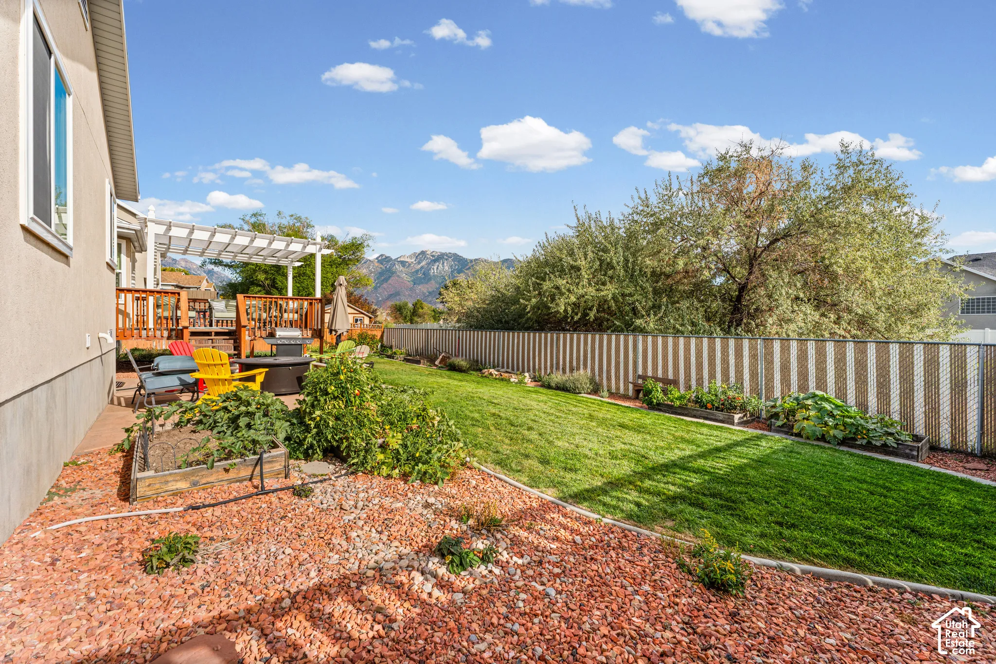 Expansive backyard featuring a manicured lawn, dedicated garden beds, and decorative rock landscaping