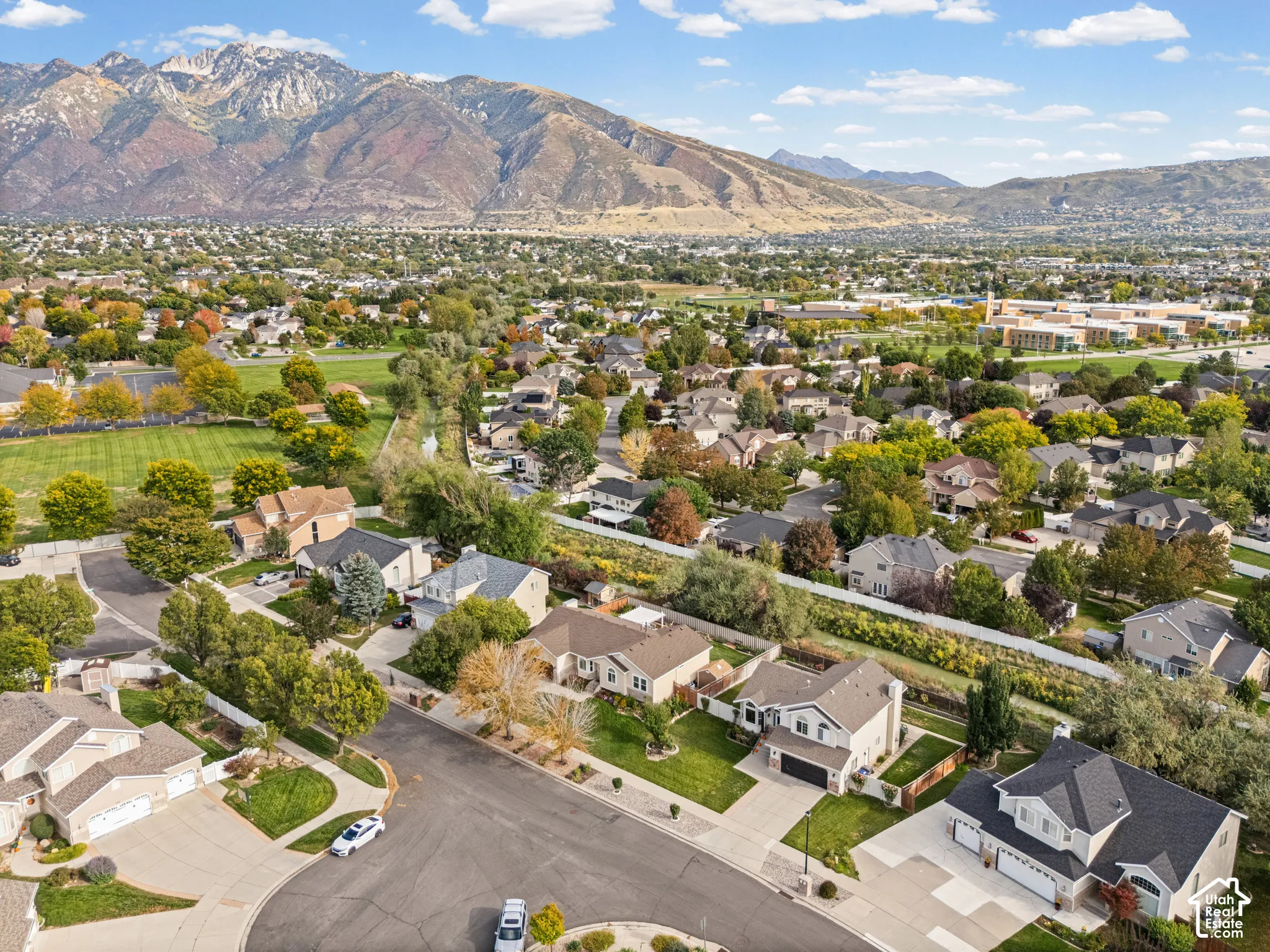 Residential neighborhood with mature trees, established street, and mountain backdrop