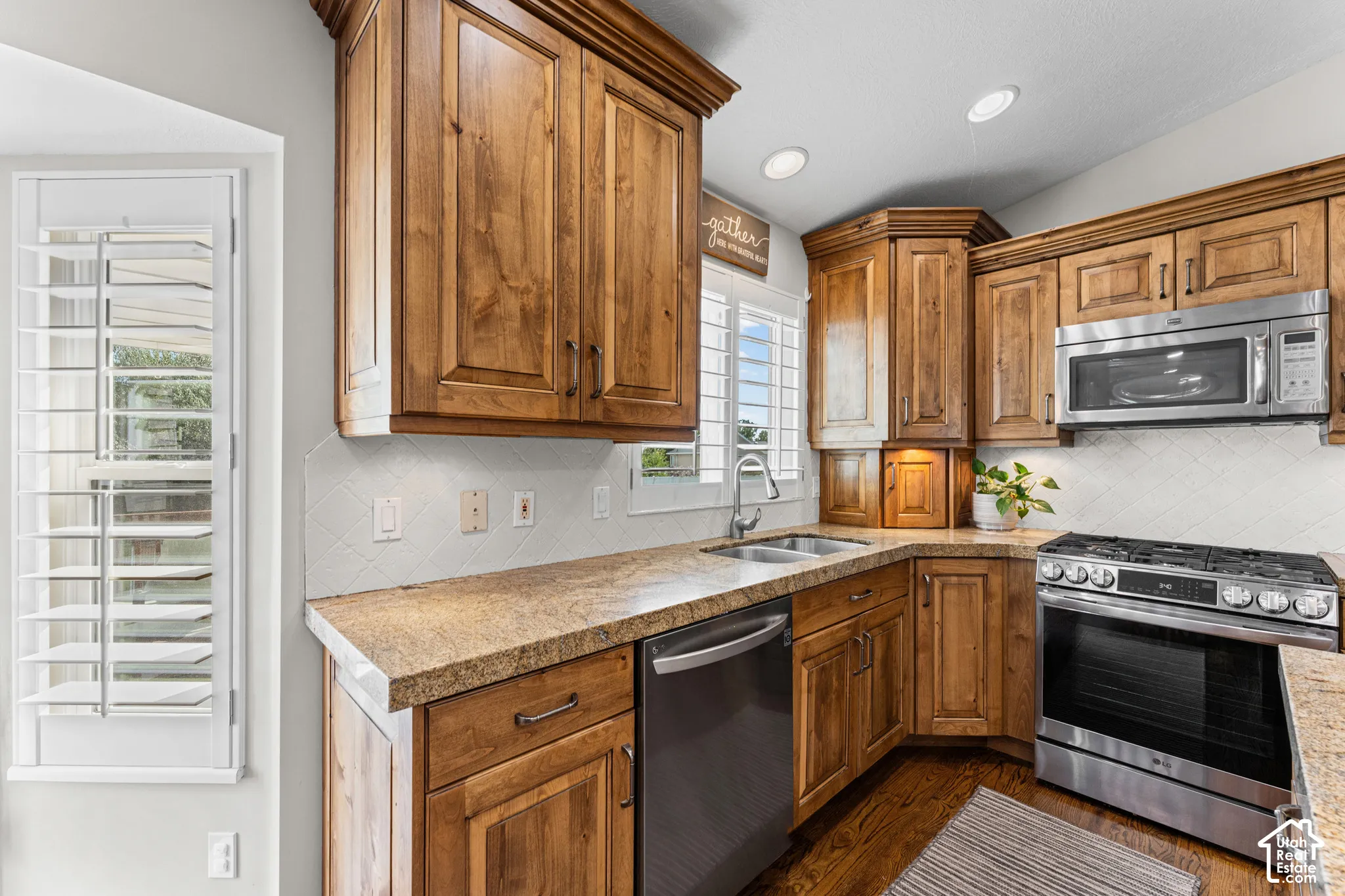Wood-finish cabinetry, stainless steel appliances, granite-style countertops, white subway tile backsplash, and recessed lighting
