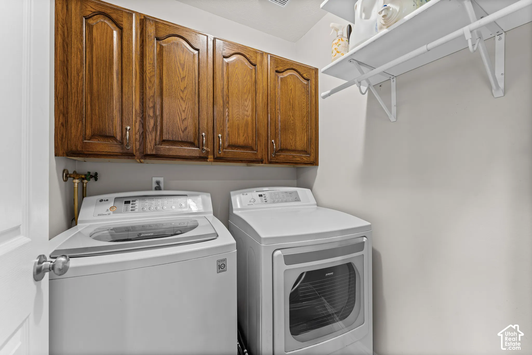 Wood-finish cabinetry with silver hardware, wall-mounted shelving, and hanging rod