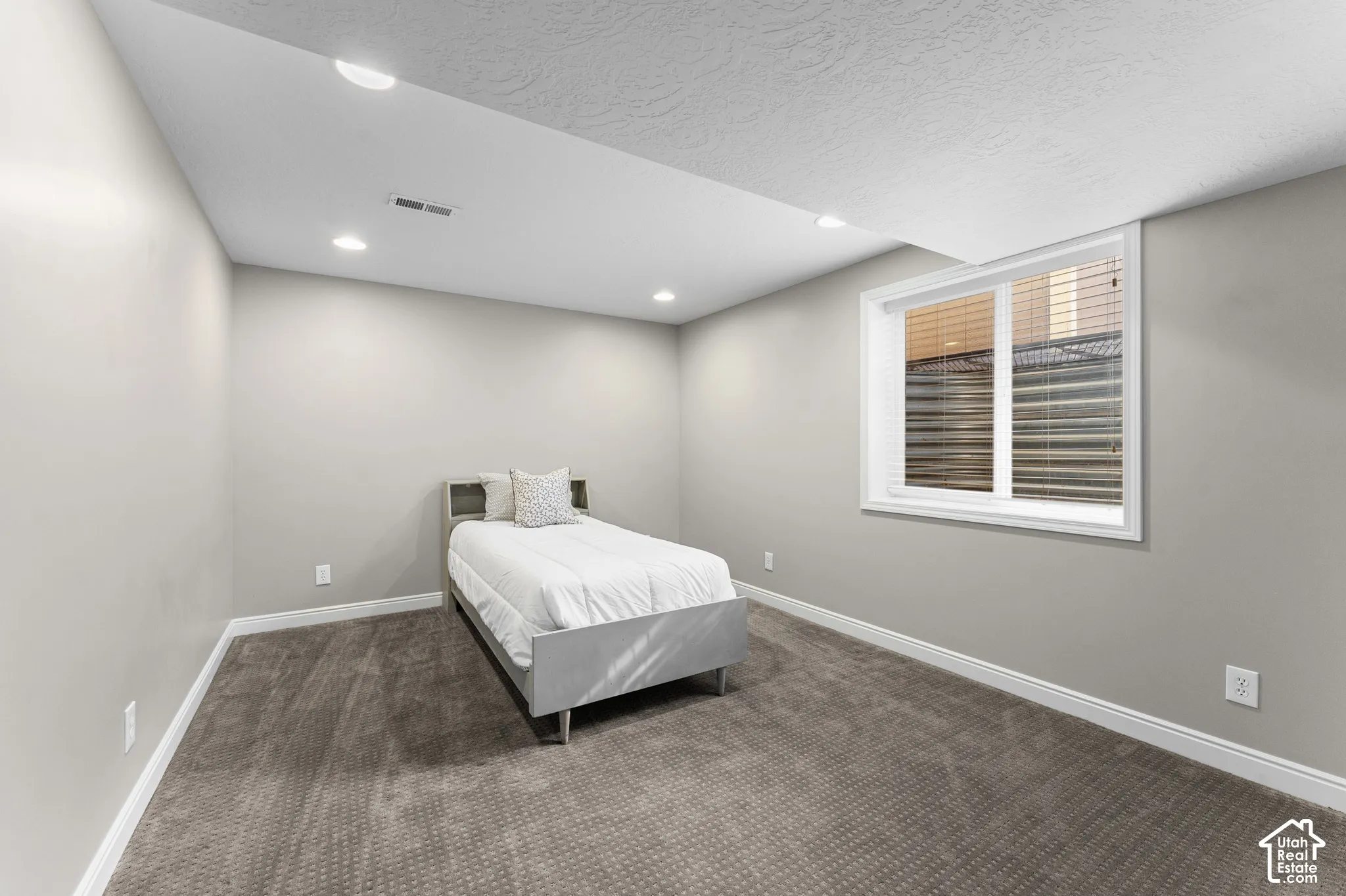 Recessed lighting illuminates the space, featuring light gray walls and patterned carpet flooring