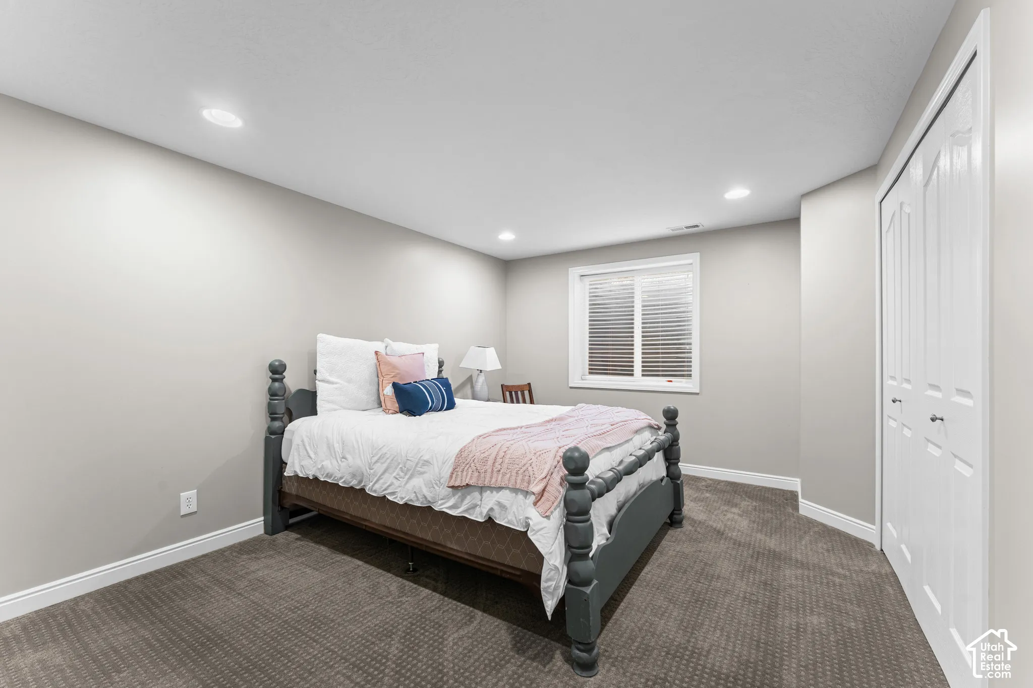 Recessed ceiling lighting, a window with horizontal blinds, neutral wall paint, white trim, and bi-fold closet doors