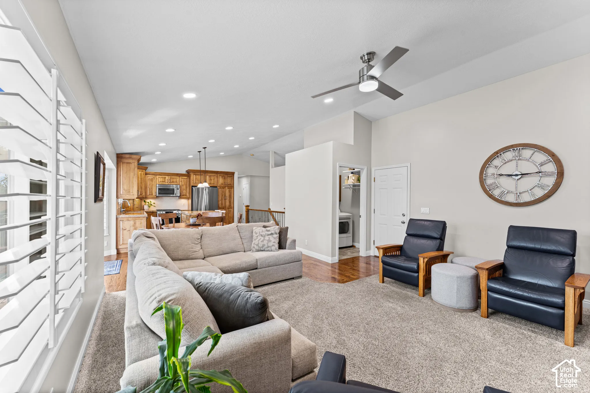 Recessed lighting throughout, ceiling fan, white window shutters, wood-finish flooring, and natural wood cabinetry