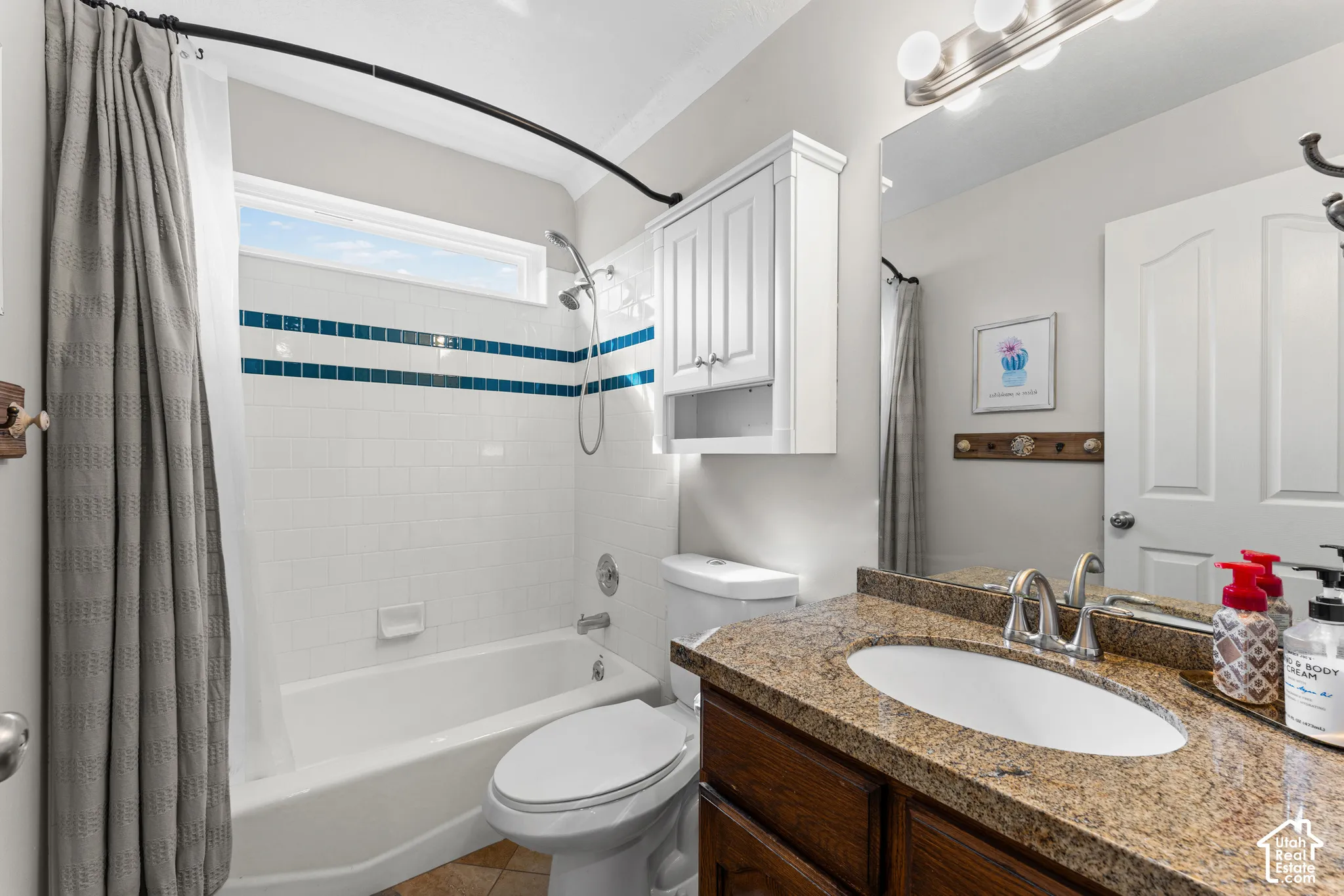 Bathroom featuring a vanity with a stone countertop, an undermount sink, and a framed mirror with integrated lighting