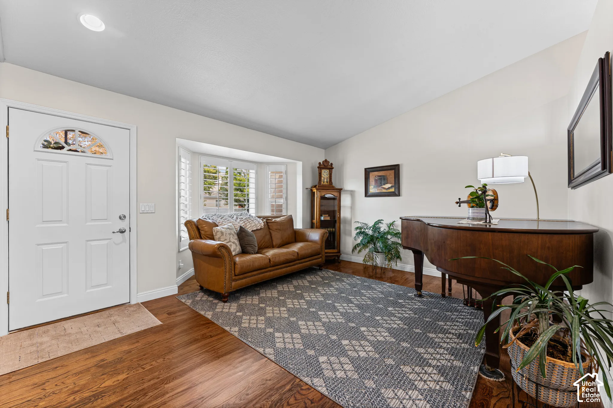 Hardwood-finish flooring, recessed ceiling lighting, bay window with shutters, and white paneled entry door with an arched window