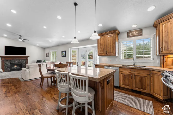 Kitchen island with stone-finish countertop, wood-finish cabinetry, and stainless steel appliances