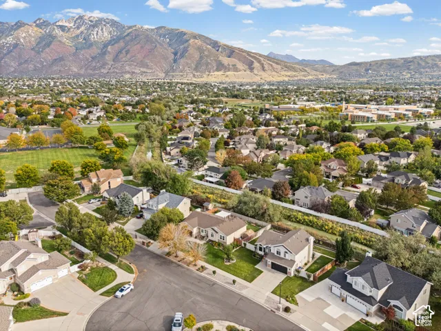 Residential neighborhood with mature trees, established street, and mountain backdrop
