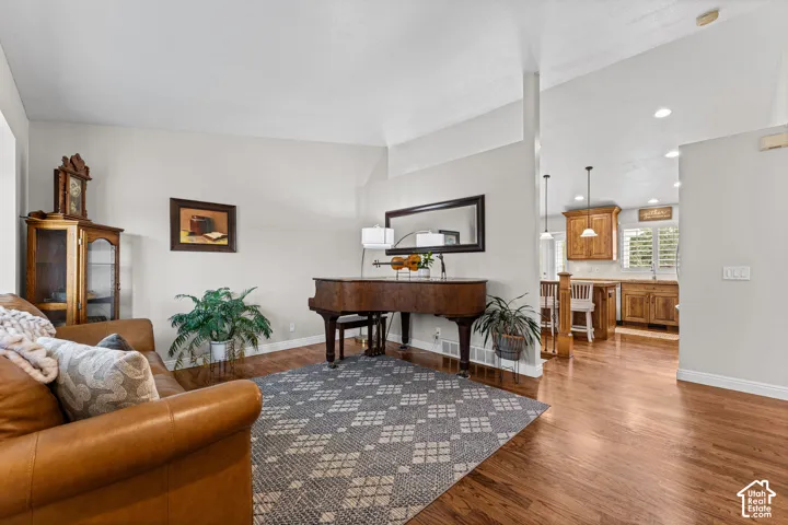 Vaulted ceilings, wood-finish flooring, recessed lighting, and wooden cabinetry with pendant lighting