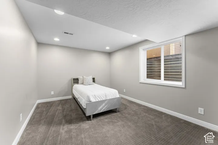 Recessed lighting illuminates the space, featuring light gray walls and patterned carpet flooring