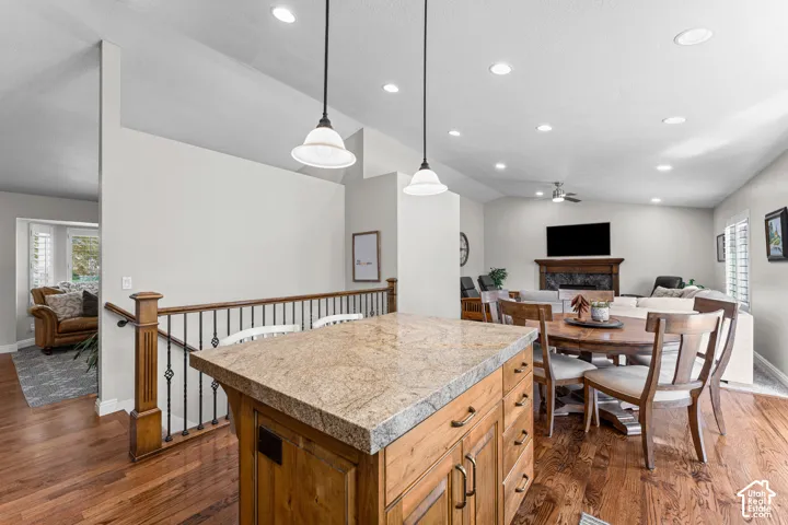 Hardwood flooring, recessed lighting, and a built-in kitchen island with a stone countertop