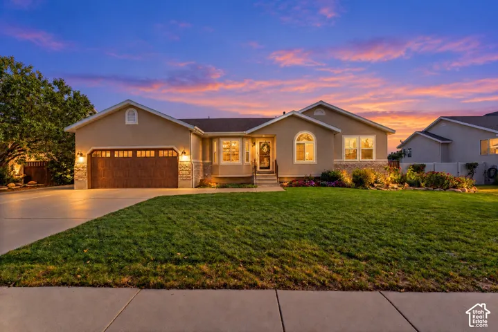 Stucco exterior with stone accents, attached two-car garage with wood-finish door, landscaped front yard, and concrete driveway