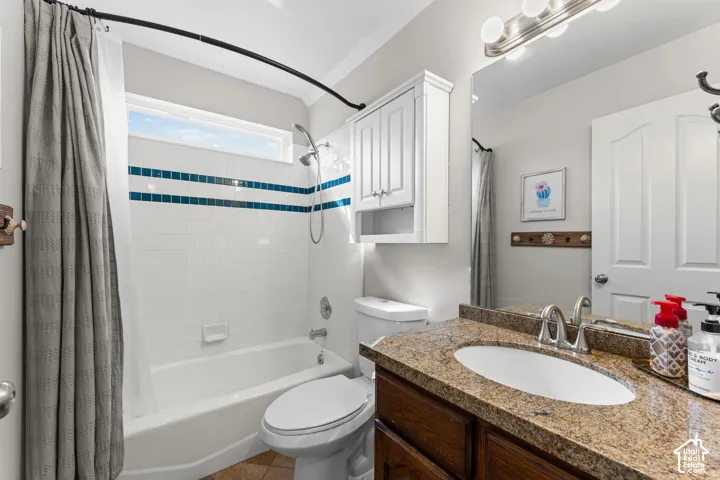 Bathroom featuring a vanity with a stone countertop, an undermount sink, and a framed mirror with integrated lighting