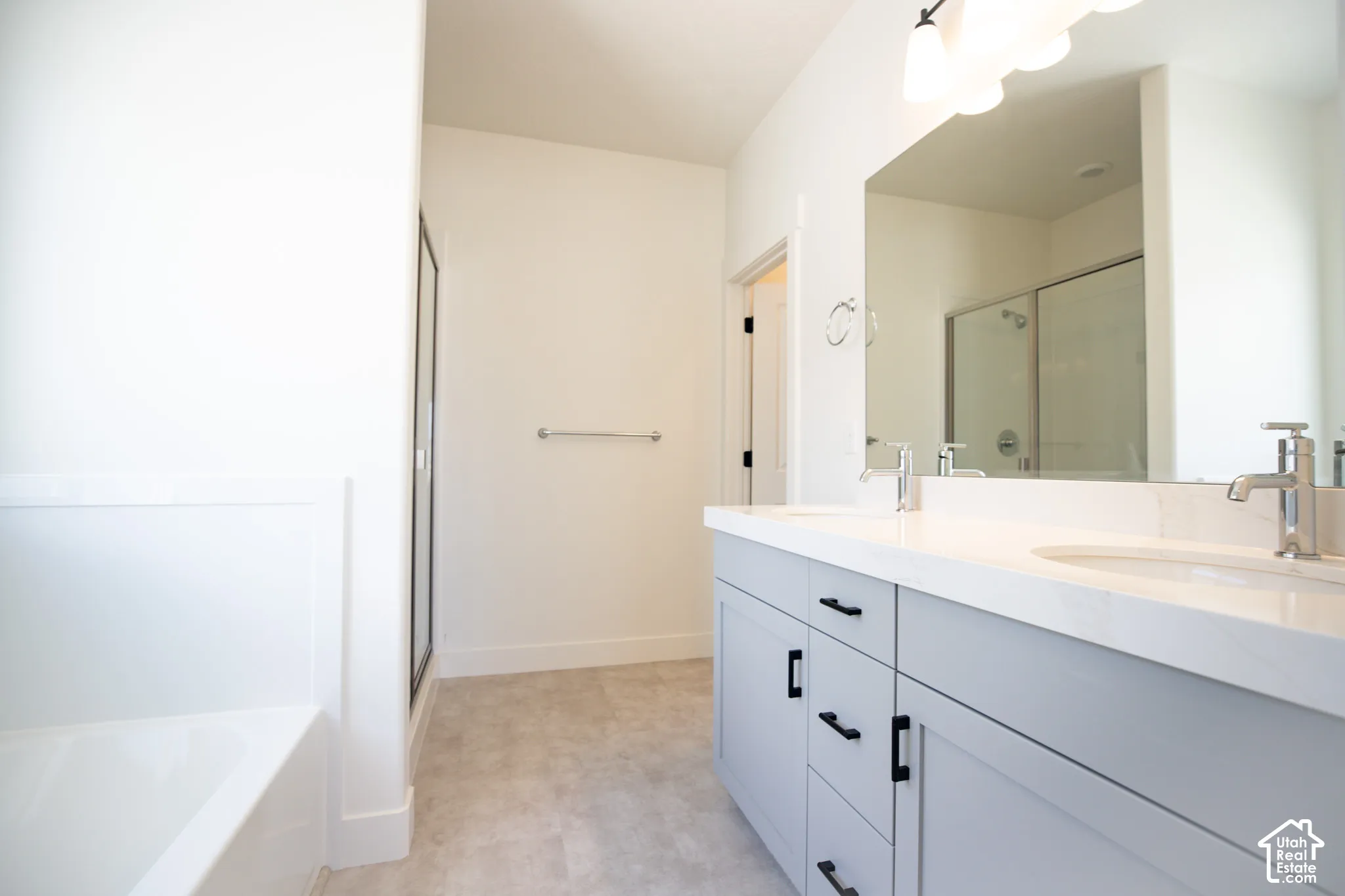 Primary bath with dual sinks, painted wood cabinets, quartz slab countertops, soaker tub and walk-in shower.
