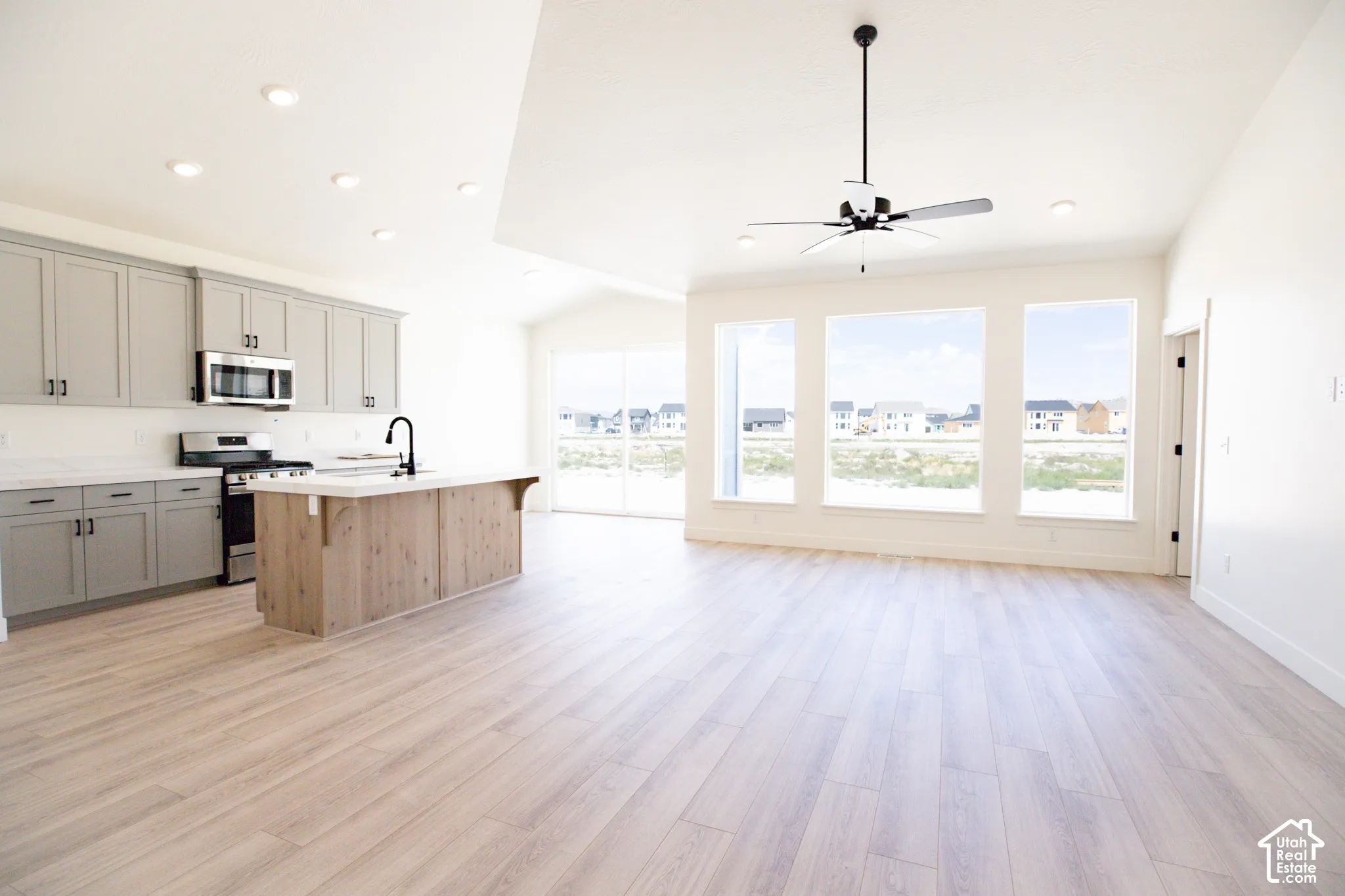 Huge Great room with vaulted ceiling, ceiling fan and great picture windows.