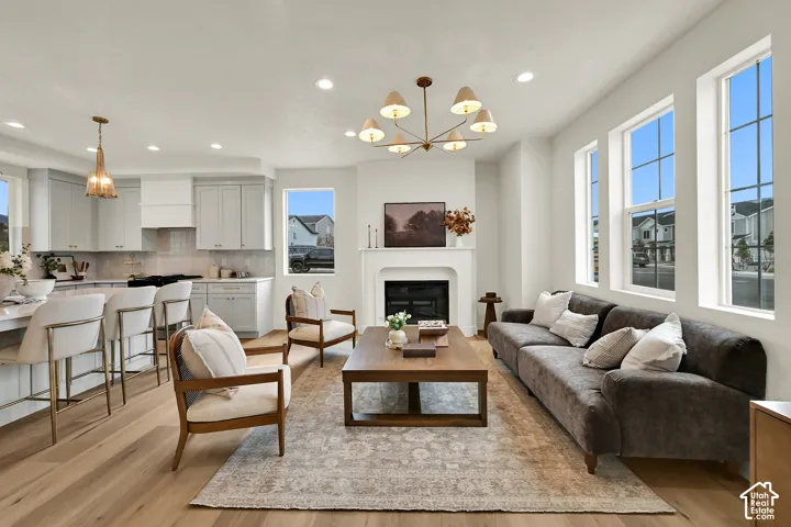 Open-concept living area featuring a fireplace, wood-finish flooring, recessed lighting, and large windows