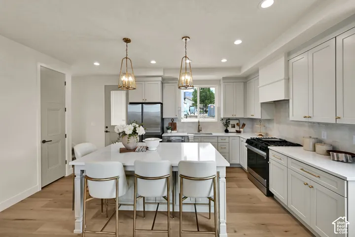 Kitchen featuring light wood-finish flooring, recessed lighting, and a white countertop island with pendant lighting