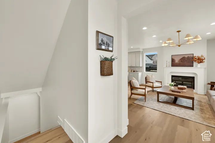 Light wood-finish flooring throughout, recessed lighting, and a white mantel over a built-in fireplace