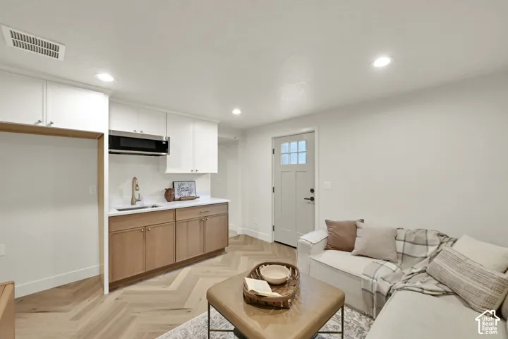 Kitchenette with integrated microwave, wood-finish flooring in a herringbone pattern, and recessed lighting