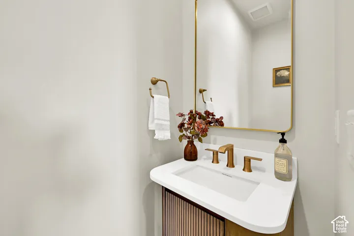 White vanity with integrated sink, matte gold faucet, and a gold-framed mirror