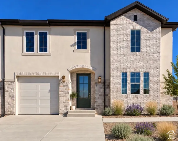 Stucco and stone exterior with architectural trim, a dark paneled front door, and a single garage door