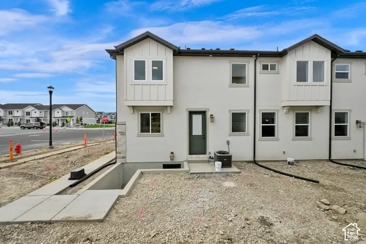 Walk Out Basement Stucco exterior with board and batten accents, multiple windows, and a concrete patio
