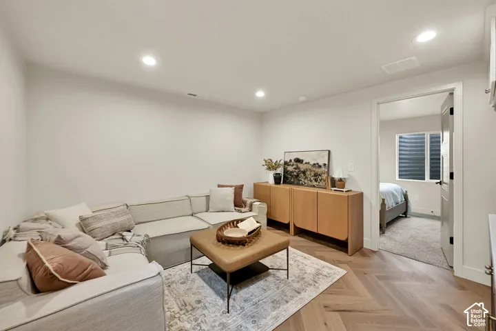 Recessed lighting, light-toned walls, and wood-finish herringbone flooring