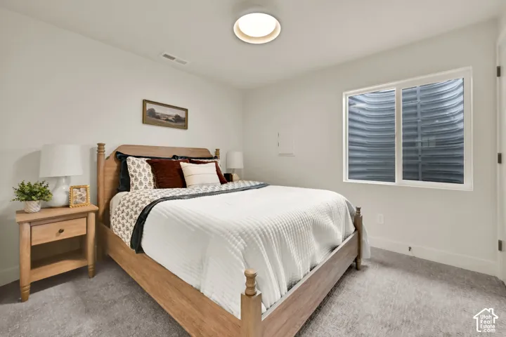Recessed ceiling light fixture, white walls, light gray carpeting, and a window with a window well
