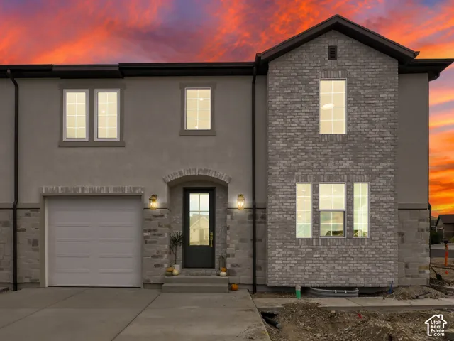 Stucco exterior with stone accents, arched entryway, two-car garage, and multiple windows