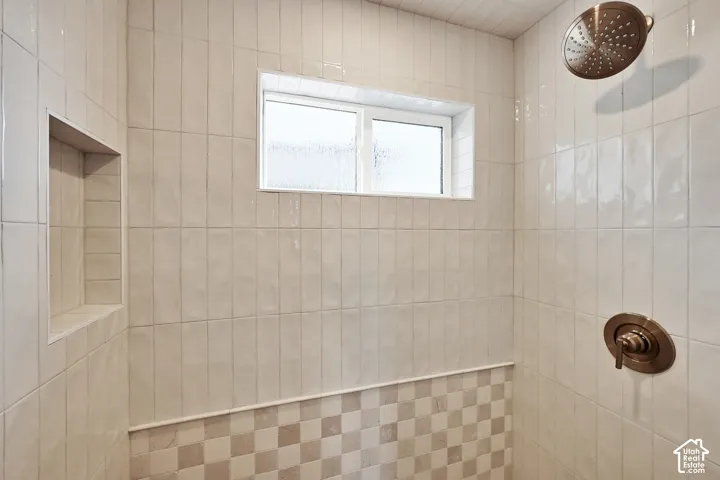 Shower featuring vertical subway tile, mosaic tile accent, built-in niche, and bronze fixtures