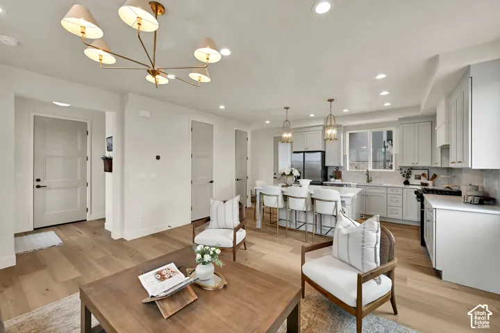 Open-concept living space featuring wood-finish flooring, recessed lighting, and a contemporary chandelier