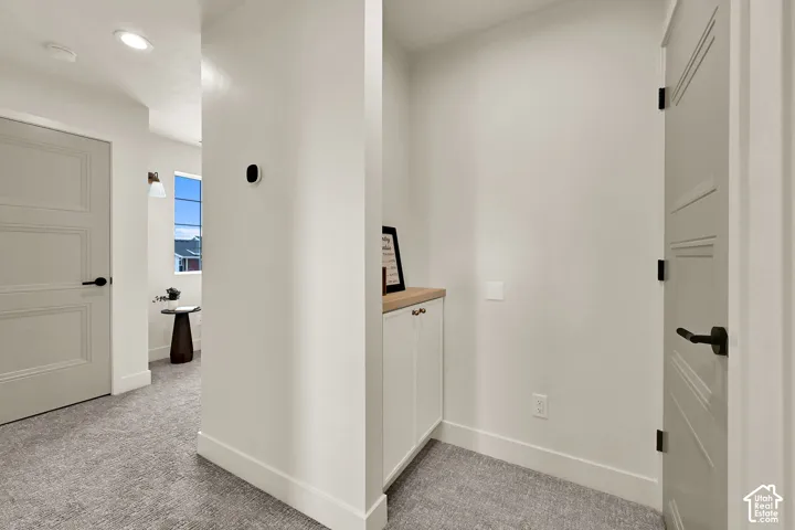 Recessed ceiling lighting, panel doors with black hardware, built-in cabinetry with a wood-finish countertop, and wall-mounted lighting