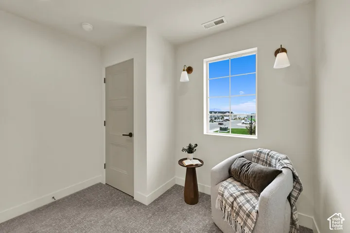 White walls complemented by textured grey carpeting, a multi-pane window, and two wall-mounted sconces