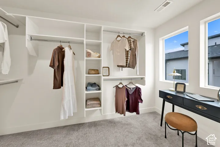 Custom closet organization system with built-in shelving, hanging rods, and soft gray carpeting