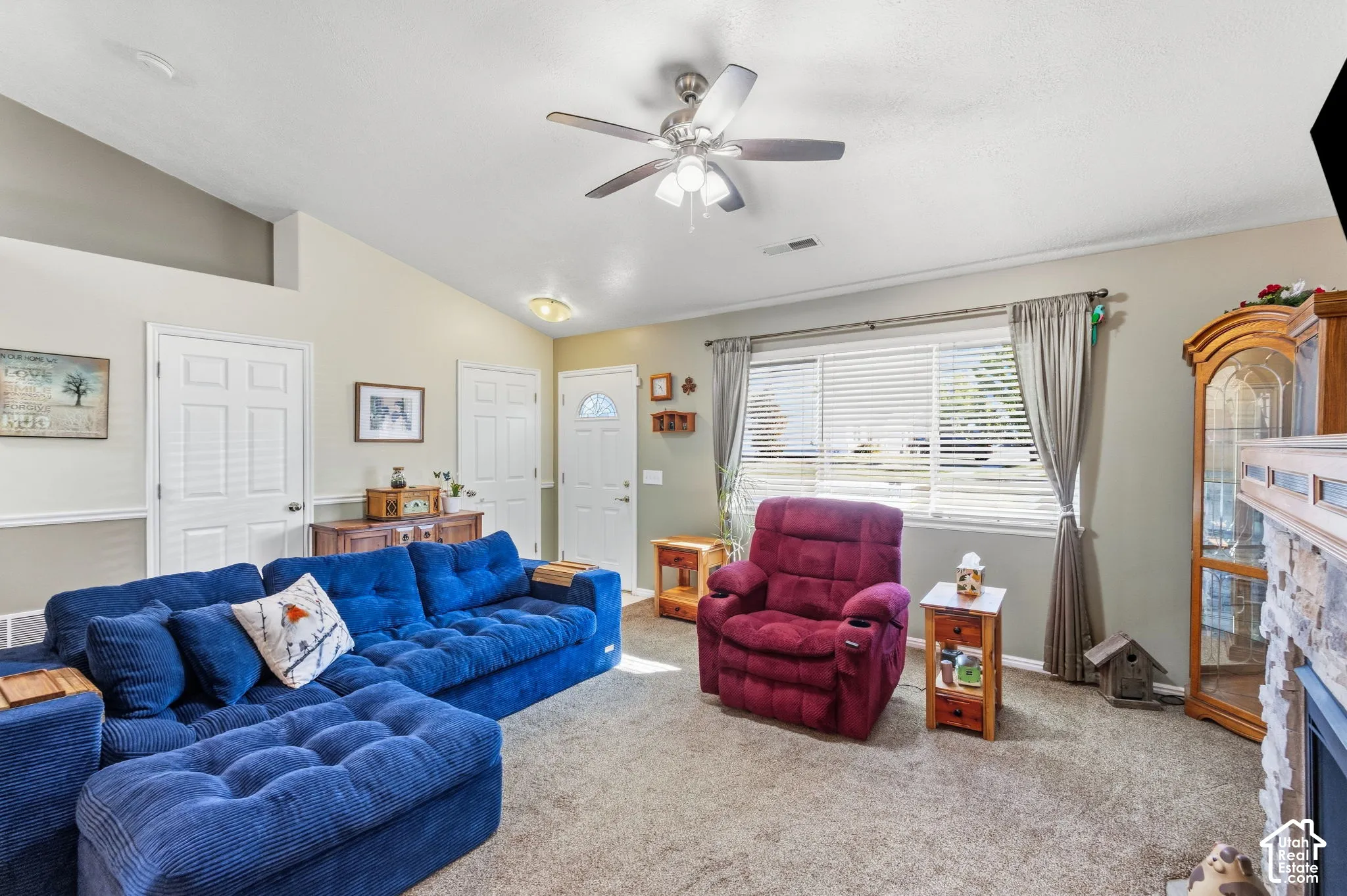 Interior living space featuring vaulted ceilings, a ceiling fan with integrated lighting, window with blinds, and carpeted flooring