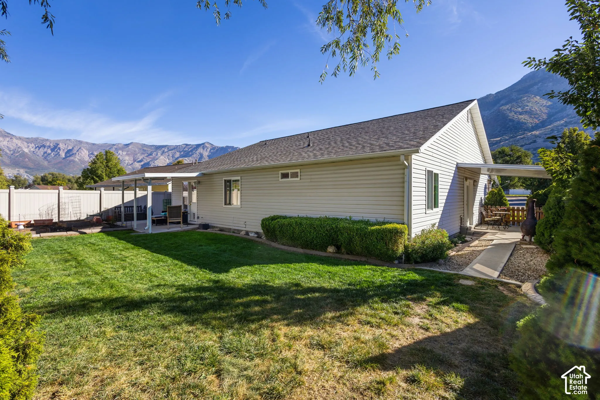 Expansive backyard with a manicured lawn, established landscaping, and covered patio area