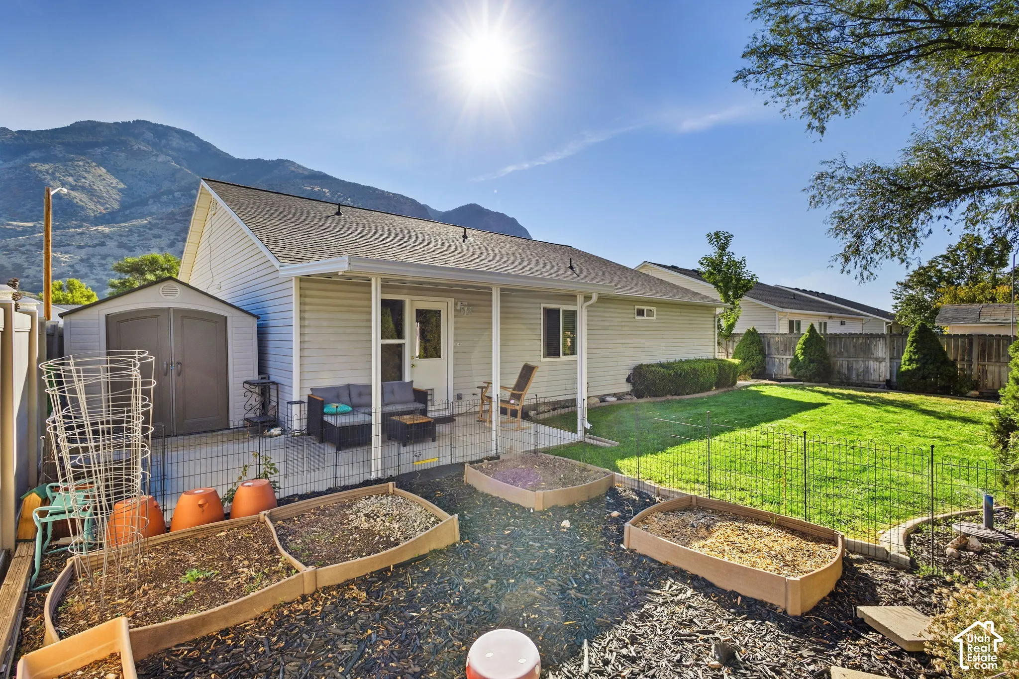 Expansive backyard with a covered patio, separate storage shed, built-in raised garden beds, and manicured lawn