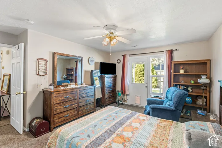 Primary bedroom with doors leading to exterior, wood-finish shelving, and ceiling fan with integrated lighting