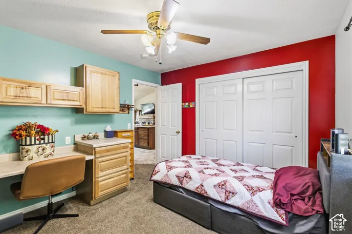 Built-in cabinetry with desk space, integrated ceiling fan, and carpeted flooring
