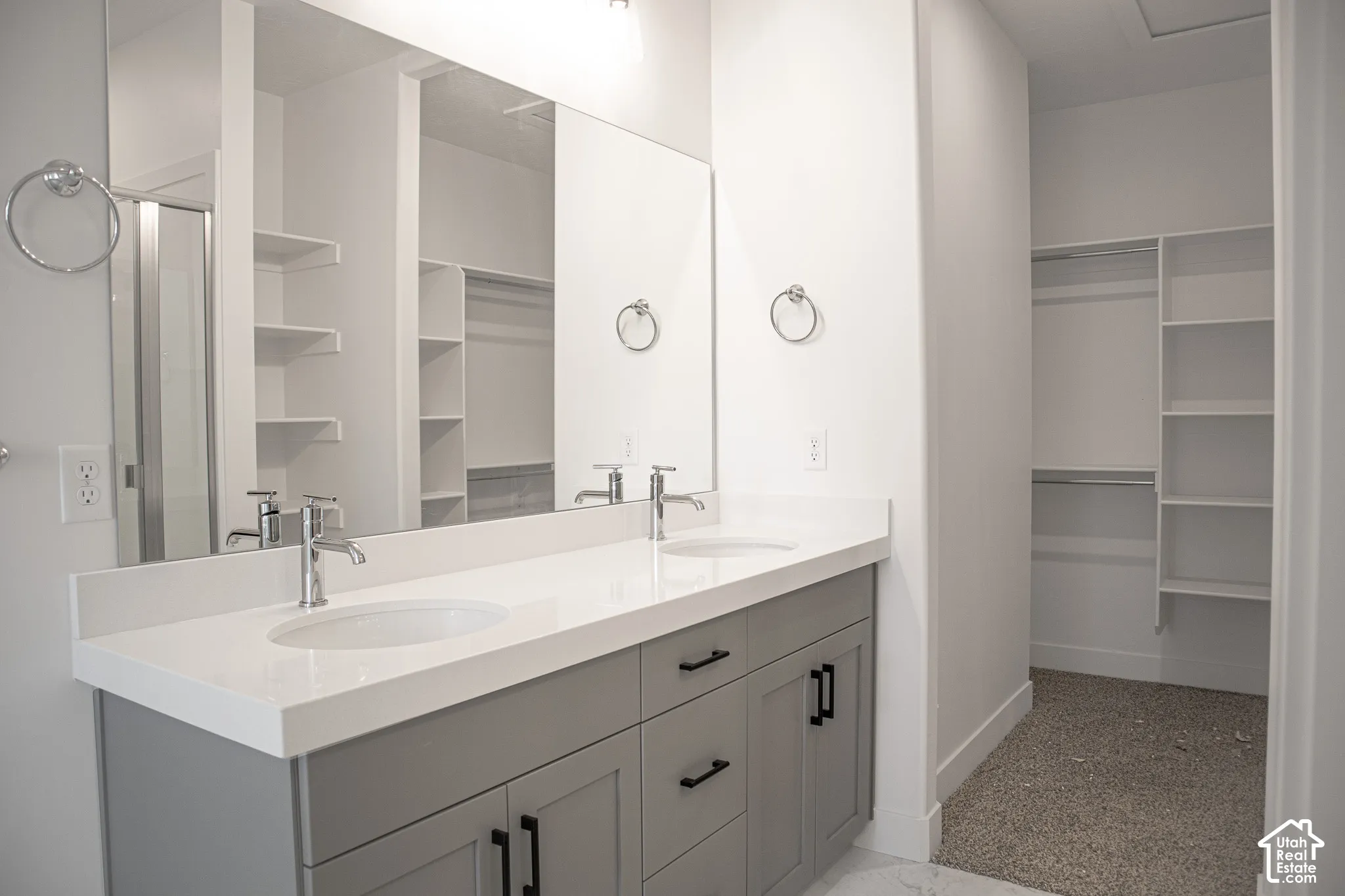 Primary bath with dual sinks, painted wood cabinets, quartz slab countertops and huge walk-in shower adjacent to walk-in closet.