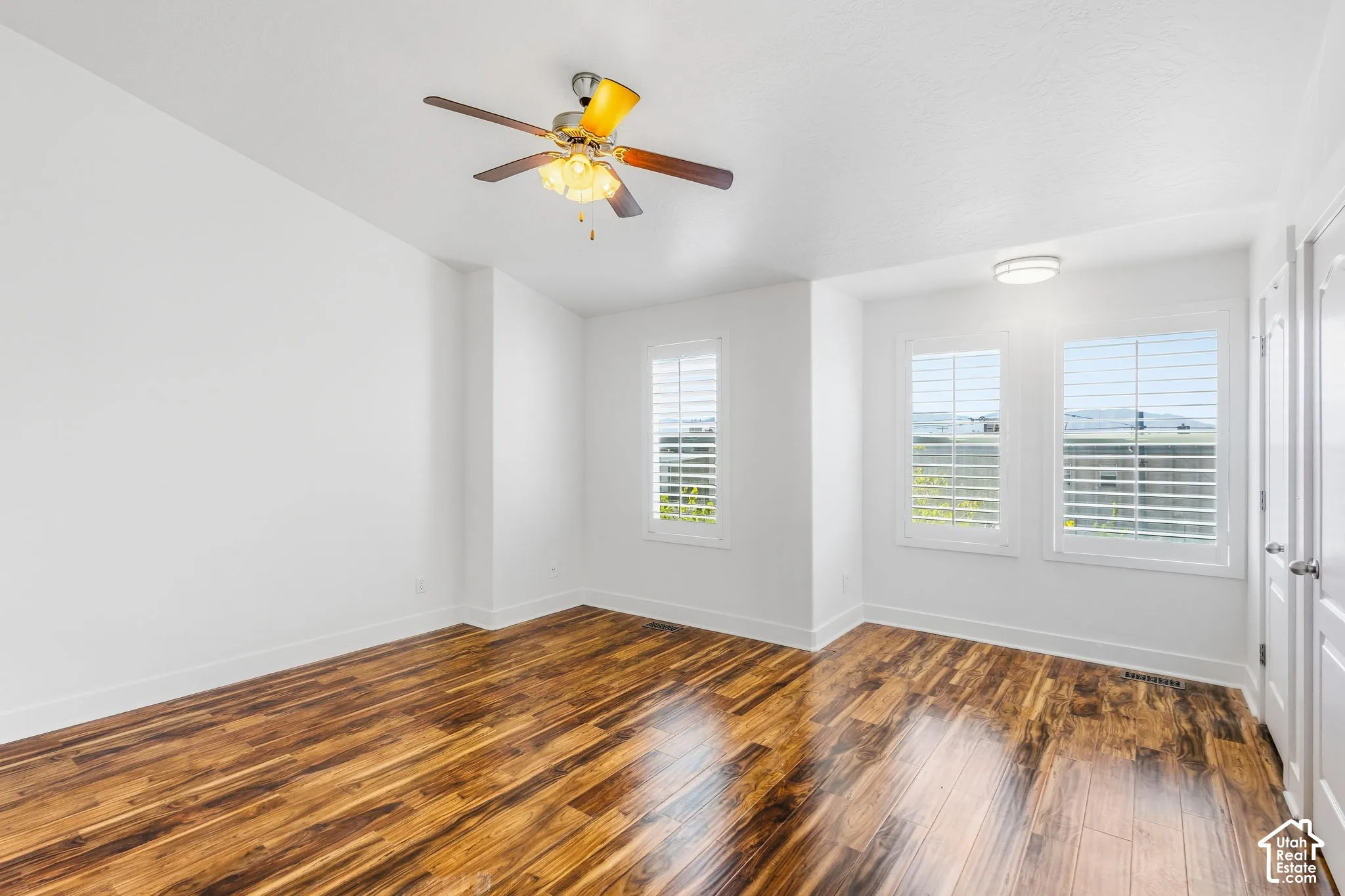 Wood-finish flooring, white walls, and a ceiling fan with integrated lighting