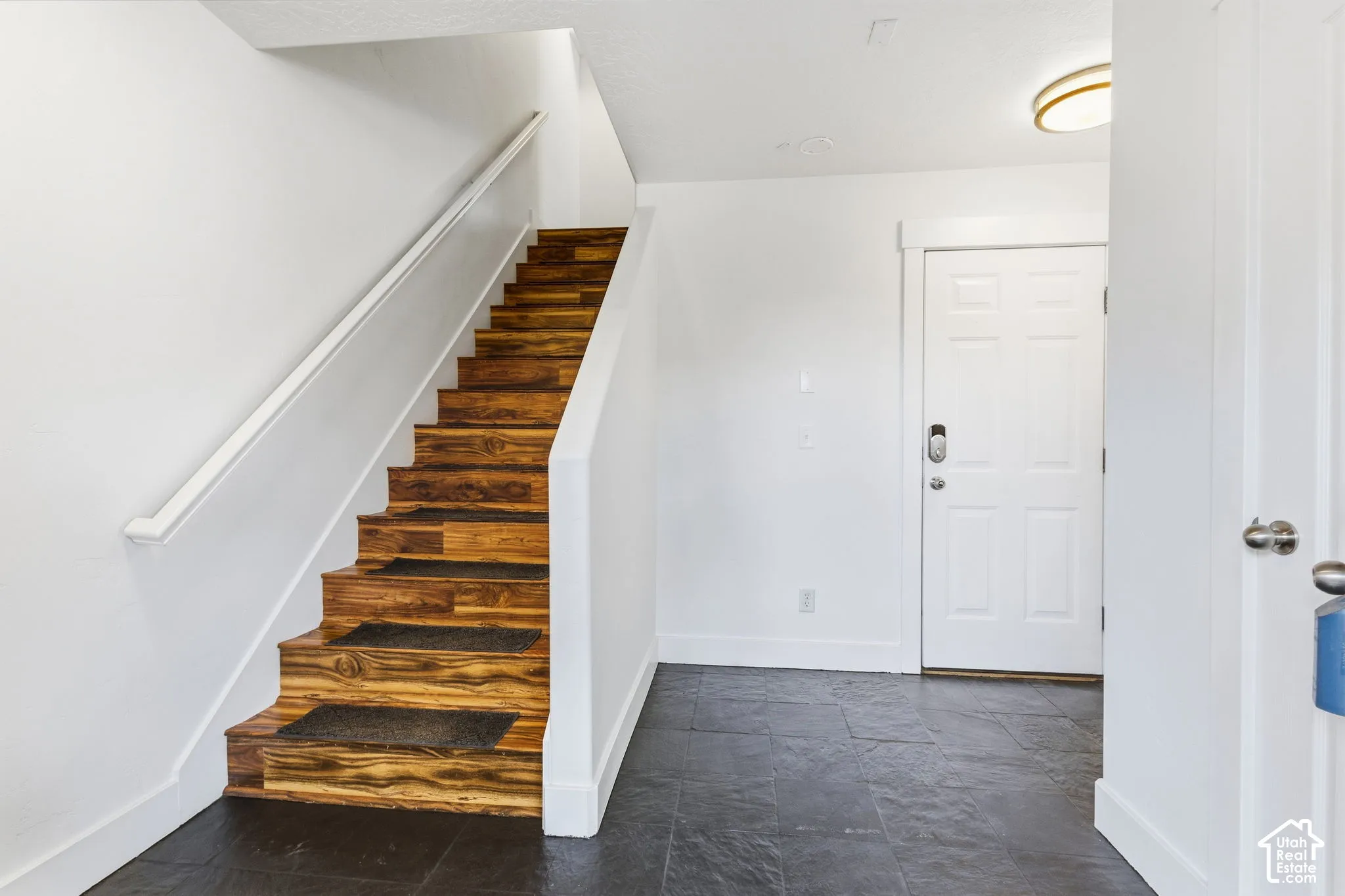 Wood-finish staircase with white handrail and risers