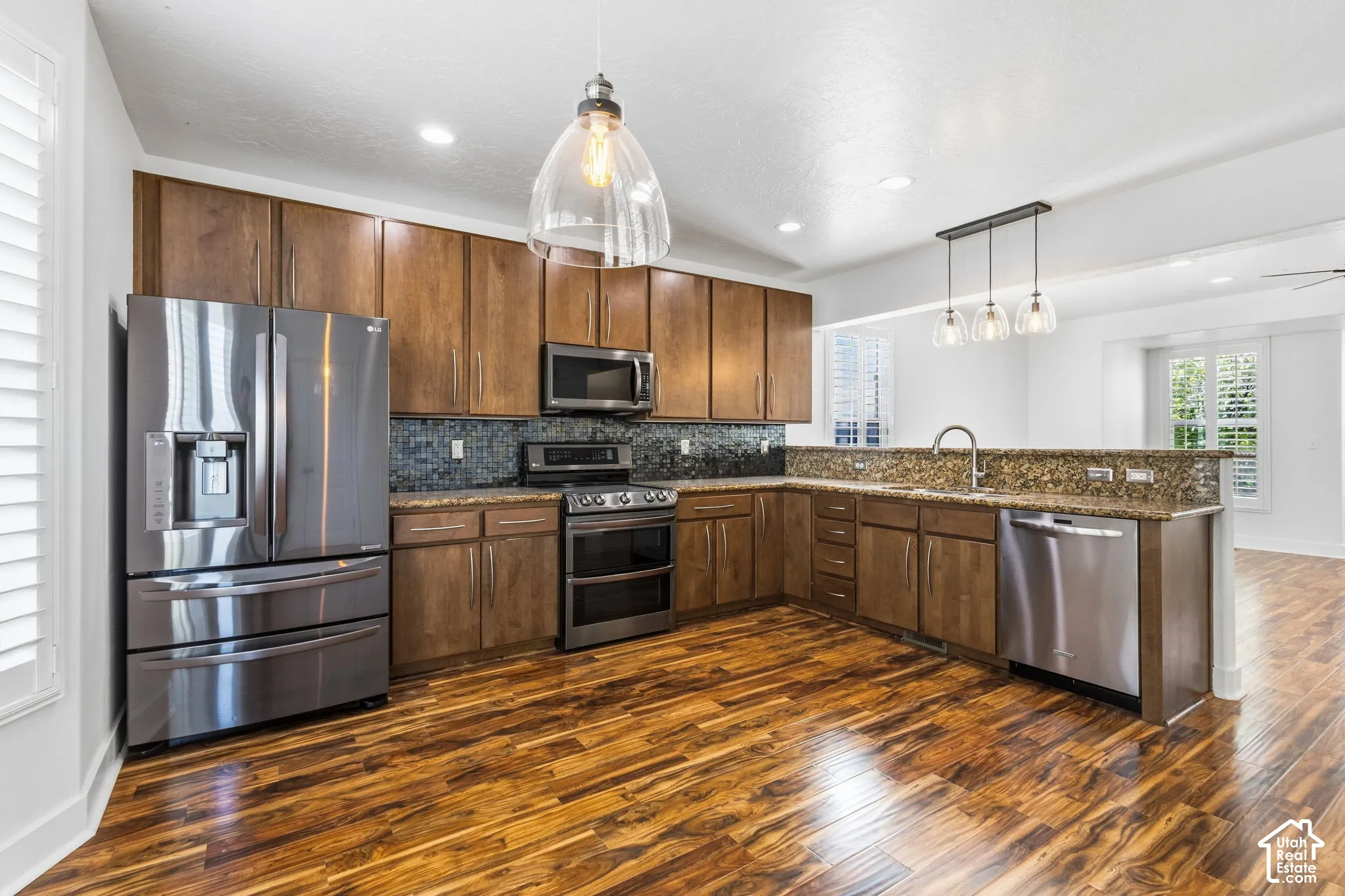 Full kitchen featuring wood-finish flooring, stainless steel appliances, upper and lower cabinetry, a mosaic tile backsplash, and recessed lighting
