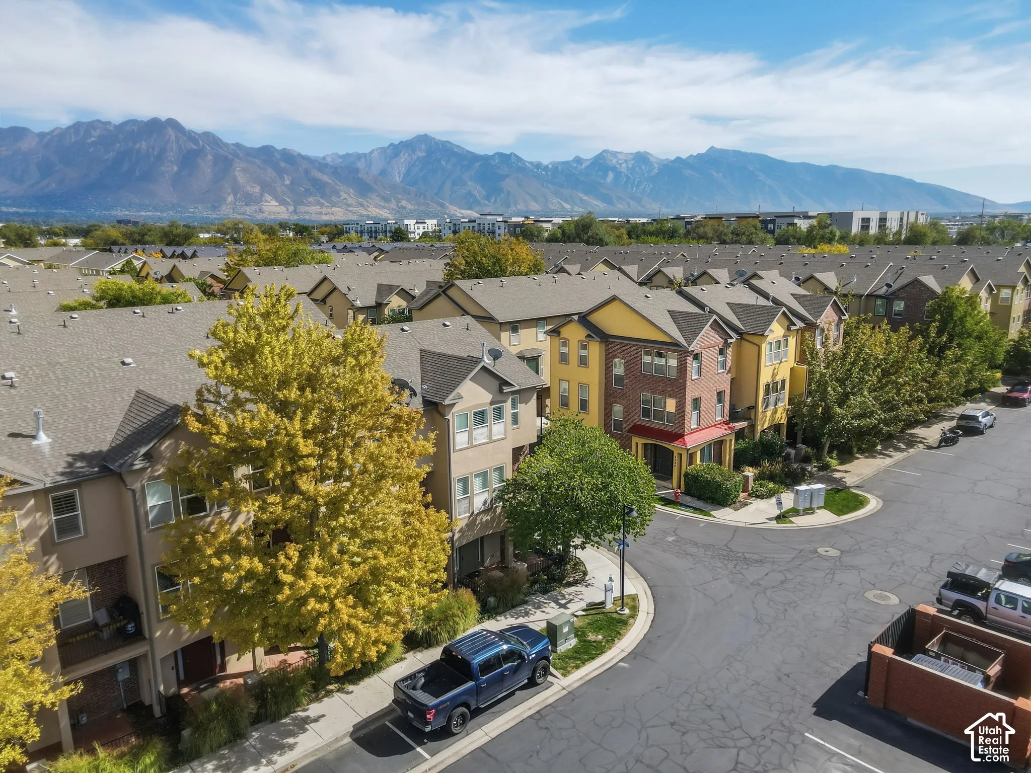 Row of townhomes featuring varied facades, pitched shingle roofs, and mature landscaping
