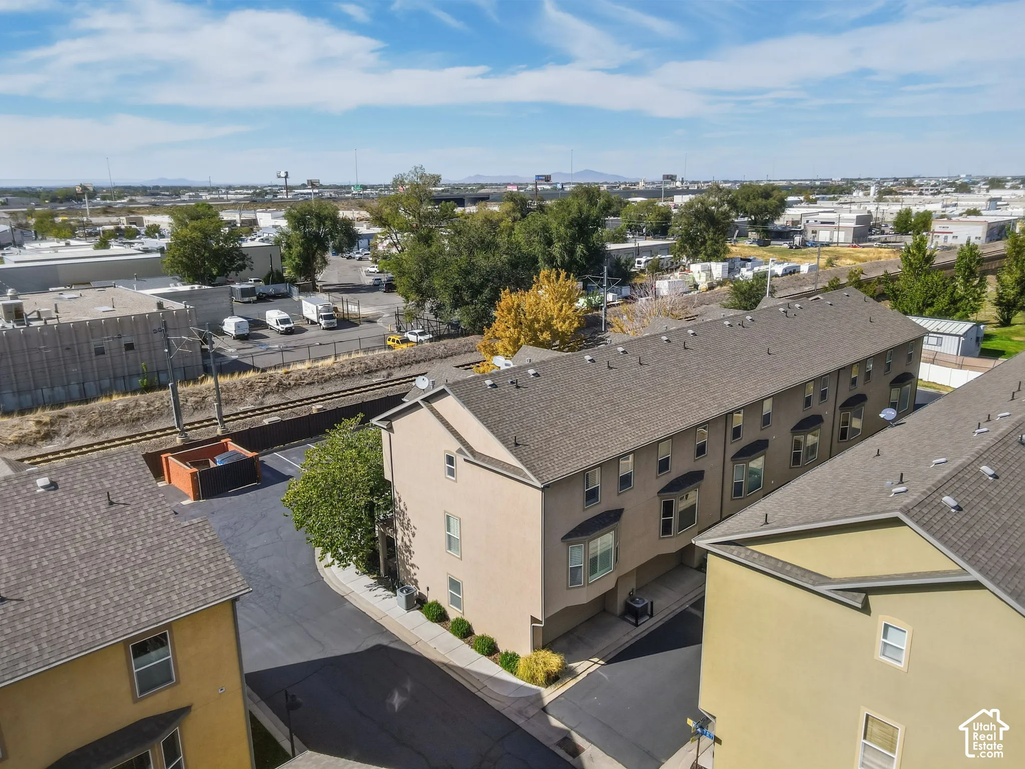 Multi-level townhouse property featuring bay windows, a paved driveway, and established landscaping