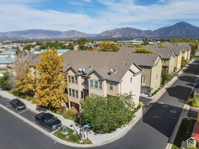 Multi-story townhome with neutral-toned siding, dark shingle roofing, and multiple windows