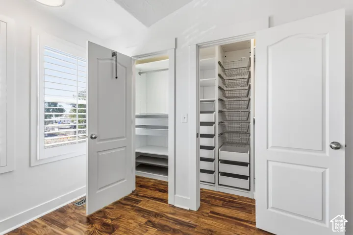 Wood-finish flooring, white walls, and a window with white louvered blinds